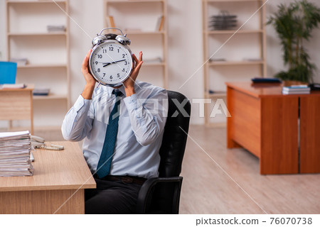 Young male employee in time management concept Young male employee in time management concept 76070738