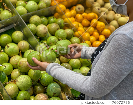 Woman wearing medical mask and buying caimito or star apple fruit  76072756