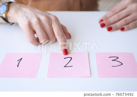 Woman showing index finger to sticker with number 2 76073492