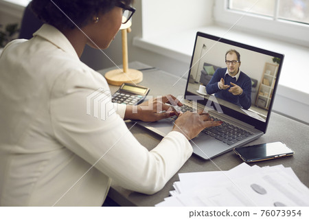Employee having online work meeting with her boss via video call on laptop computer 76073954