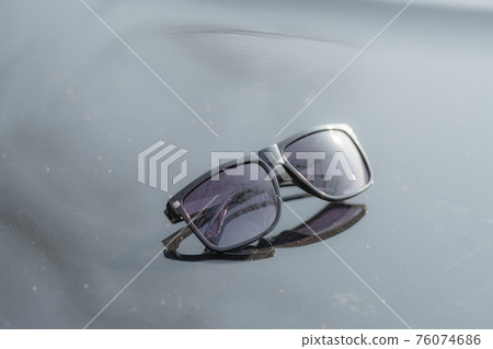 Classic Sunglasses design for men and ladies with black lenses and black frame shoot outside in a summer day closeup. Selective focus 76074686