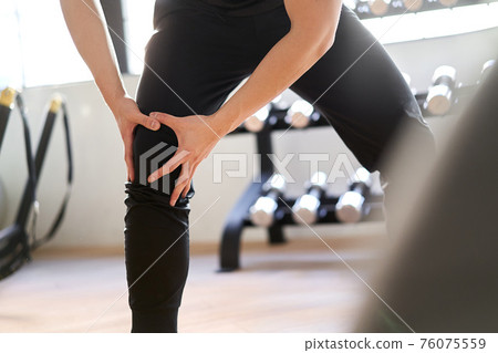 Asian man feeling pain in knee joint in training gym Asian man feeling pain in knee joint in training gym 76075559