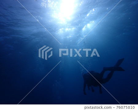 Silhouette of a diver swimming in the sea 2 76075810