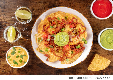 Nachos with tequila and dips, overhead flat lay shot Nachos with tequila and dips, overhead flat lay shot 76076332