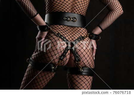 Beautiful woman in a full body mesh stands with her back in bondage set 76076718