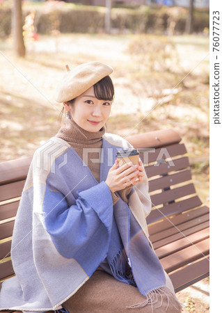 Woman drinking coffee in the autumn park 76077723