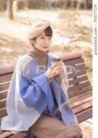 Woman drinking coffee in the autumn park Woman drinking coffee in the autumn park 76077724