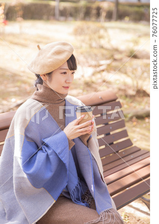Woman drinking coffee in the autumn park Woman drinking coffee in the autumn park 76077725