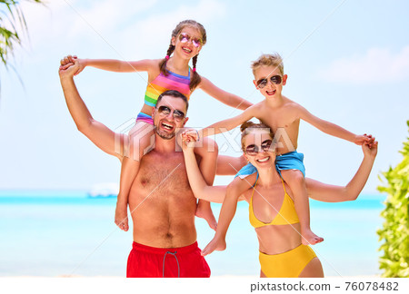 Happy family in colorful swimsuits on beach 76078482