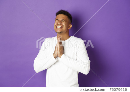 Image of desperate african-american guy pleading to God, holding hands in pray and begging for something, making wish, standing worried over purple background Image of desperate african-american guy pleading to God, holding hands in pray and begging for something, making wish, standing worried over purple background 76079616