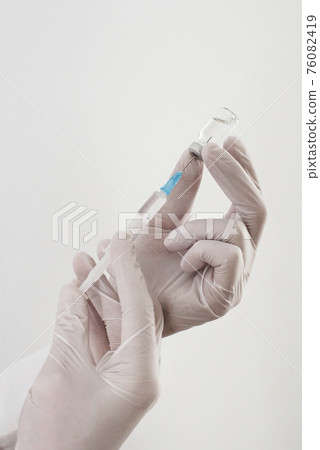 Doctor hands holding a vaccine bottle and syringe,beginning of worldwide mass vaccination for coronavirus COVID-19,influenza or flu,world immunization concept. Selective focus 76082419