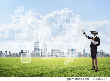 Camera headed woman standing on green grass against modern cityscape Camera headed woman standing on green grass against modern cityscape 76082716