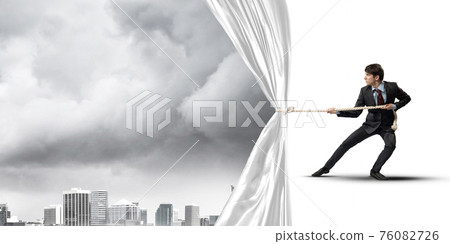 Young man opening white curtain and presenting modern city landscape Young man opening white curtain and presenting modern city landscape 76082726