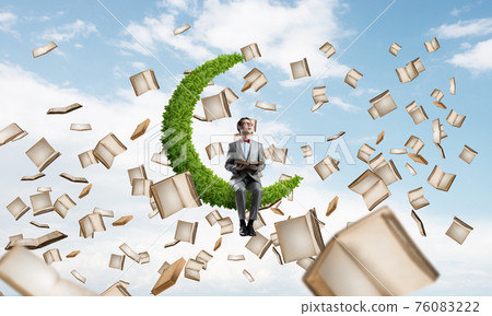 Young businessman or student studying the science and books flying around Young businessman or student studying the science and books flying around 76083222