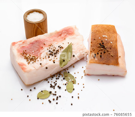 raw lard two pieces and salt, spices and bay leaf on white background, pork fat 76085655