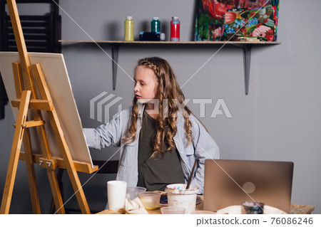 a young female student of an art school studies online remotely via the Internet. 76086246