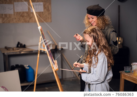 a young female Artist teaches a girl student to draw in the Studio. Private lesson. 76086363