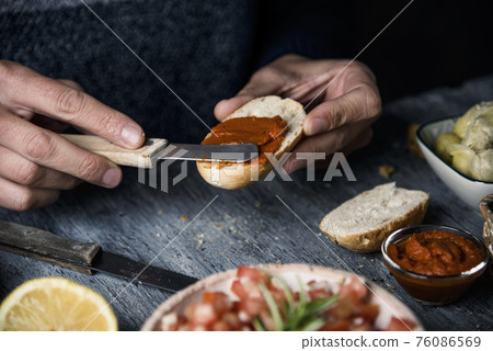man spreads vegan sobrasada on a piece of bread 76086569