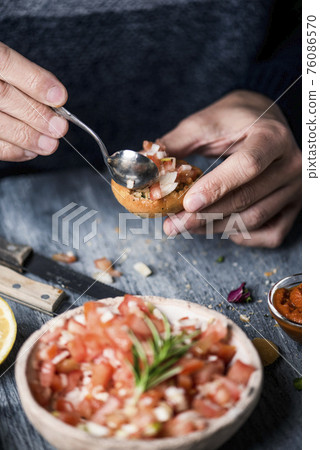 man topping a vegan appetizer with tomato salad 76086570