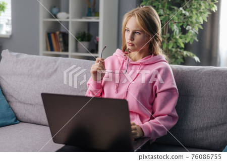 Woman using laptop on sofa Woman using laptop on sofa 76086755
