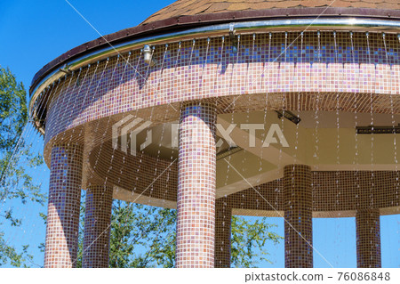 gazebo roof with water pipe and fountain in a city park, bright summer day gazebo roof with water pipe and fountain in a city park, bright summer day 76086848