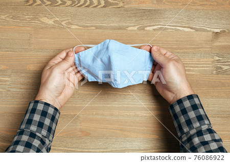 hands with handmade breathing mask on a wooden background, checkered shirt in rustic style, health care prevention of coronavirus infection, as well as other viruses and pollution hands with handmade breathing mask on a wooden background, checkered shirt in rustic style, health care prevention of coronavirus infection, as well as other viruses and pollution 76086922