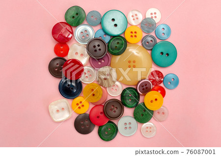Buttons for clothes on a pink colored background. Sewing accessories. 76087001