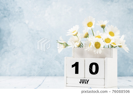cube calendar for July with daisy flowers over blue cube calendar for July with daisy flowers over blue 76088506