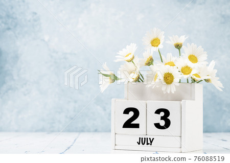 cube calendar for July with daisy flowers over blue cube calendar for July with daisy flowers over blue 76088519