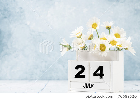 cube calendar for July with daisy flowers over blue cube calendar for July with daisy flowers over blue 76088520
