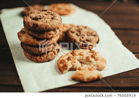 Chocolate cookies on parchment paper. Broken biscuits on a wooden table. Selective focus. 76088919