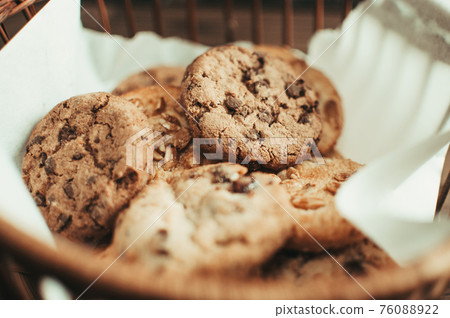 Cookies with chocolate lies in a wicker basket. A basket with gluten free cookies on a wooden table. Selective focus. 76088922