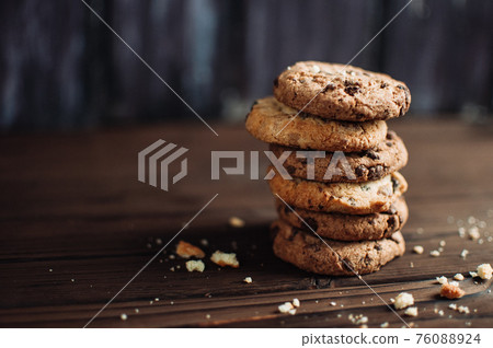 Cookies with chocolate worth a stack on a wooden table in a rustic style. Crumbs from biscuits on wooden boards. Selective focus Cookies with chocolate worth a stack on a wooden table in a rustic style. Crumbs from biscuits on wooden boards. Selective focus 76088924
