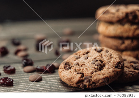A stack of oatmeal cookies with chocolate pieces and candied fruits lies on a wooden table. Rustic table. Vintage toning. Dietary useful cookies without gluten. Copy space. 76088933