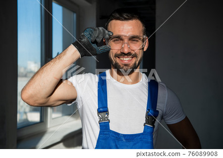 The laborer in gloves and goggles smiles kindly 76089908