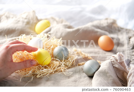 Hand holding Organic naturally dyed yellow and gray Easter eggs. 76090463