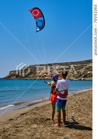 Trainer teaches woman to go kitesurfing on sea sand beach Trainer teaches woman to go kitesurfing on sea sand beach 76091068