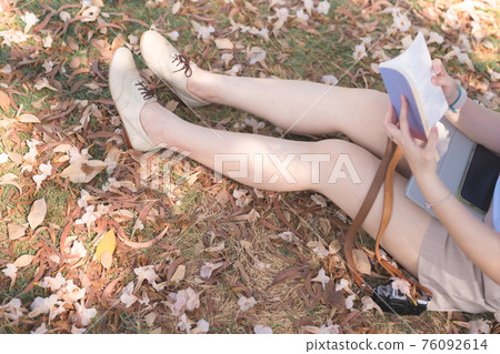 asian woman relax and read book under tree with pink flower on floor in spring season asian woman relax and read book under tree with pink flower on floor in spring season 76092614