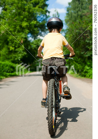 Kid riding bicycle 76092836