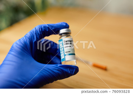 Doctor, nurse hand in blue gloves holding coronavirus covid-19 vaccine 76093828