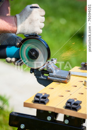 Man using angle grinder to cut metal bar Man using angle grinder to cut metal bar 76094081
