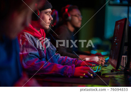 International gaming event. Arena for conducting esports competitions. Young players with headphones are playing a popular online game. 76094833