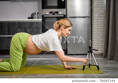 Pregnant Woman Doing Cat Pose Marjariasana Exercise At Home, Watching Video Online Lesson 76095144