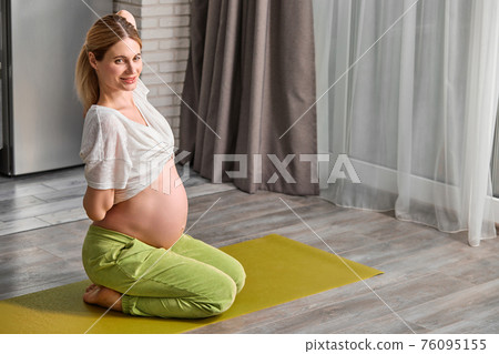 side view on pregnant woman stretching body at home, going to do yoga exercises on floor side view on pregnant woman stretching body at home, going to do yoga exercises on floor 76095155