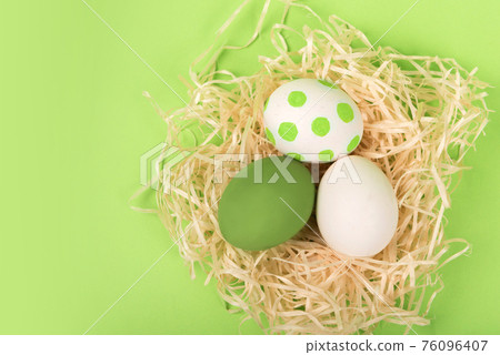 Nest with painted easter eggs on green background Nest with painted easter eggs on green background 76096407