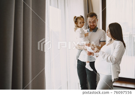 Pregnant mom dad and little daughter look at photo Pregnant mom dad and little daughter look at photo 76097556