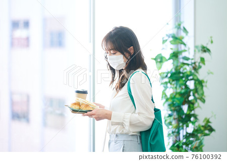 年輕女子戴著面具在咖啡館吃飯 76100392