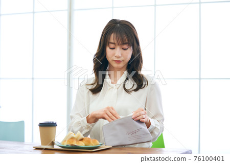 Young woman wearing a mask and eating at a cafe 76100401