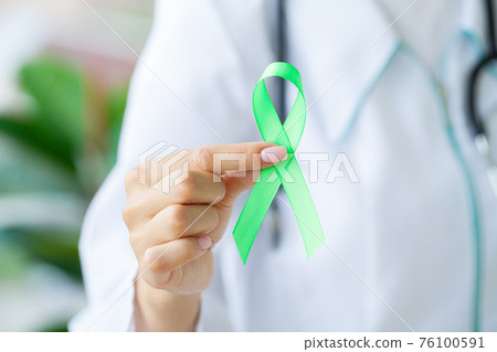 Green ribbon in hand as a symbol to awareness Lymphoma cancer Green ribbon in hand as a symbol to awareness Lymphoma cancer 76100591