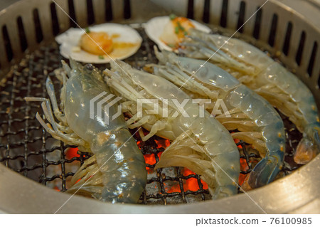 Raw fresh shrimp is grilled on a charcoal stove 76100985